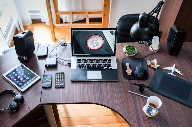 Busy office desk with a laptop, notebook, and coffee cup